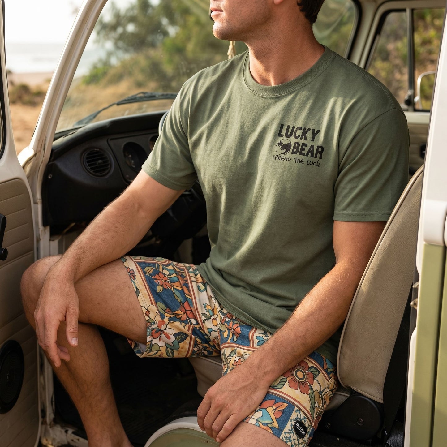 Close-up of a model in a vintage Volkswagen seat, wearing a Spread the Luck tee with visible logo and fabric detail, natural lighting.