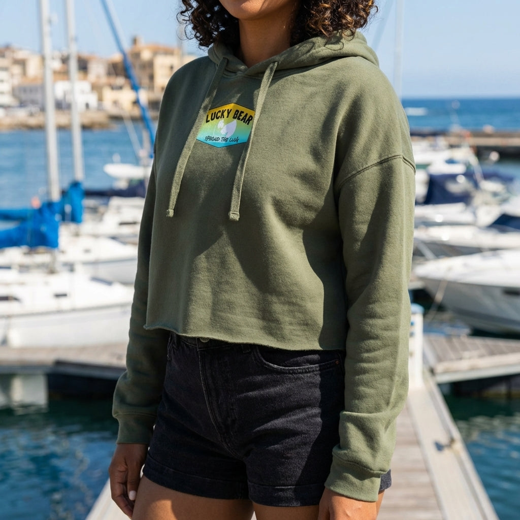 Close-up of Orange Dreaming Crop Hoodie displayed on a model near a marina, showcasing textured fabric and raw hem detail.
