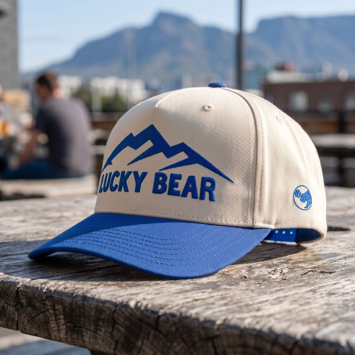 Close-up of blue Sierra 5 panel hat on textured outdoor table, showcasing stitch details and fabric weave.