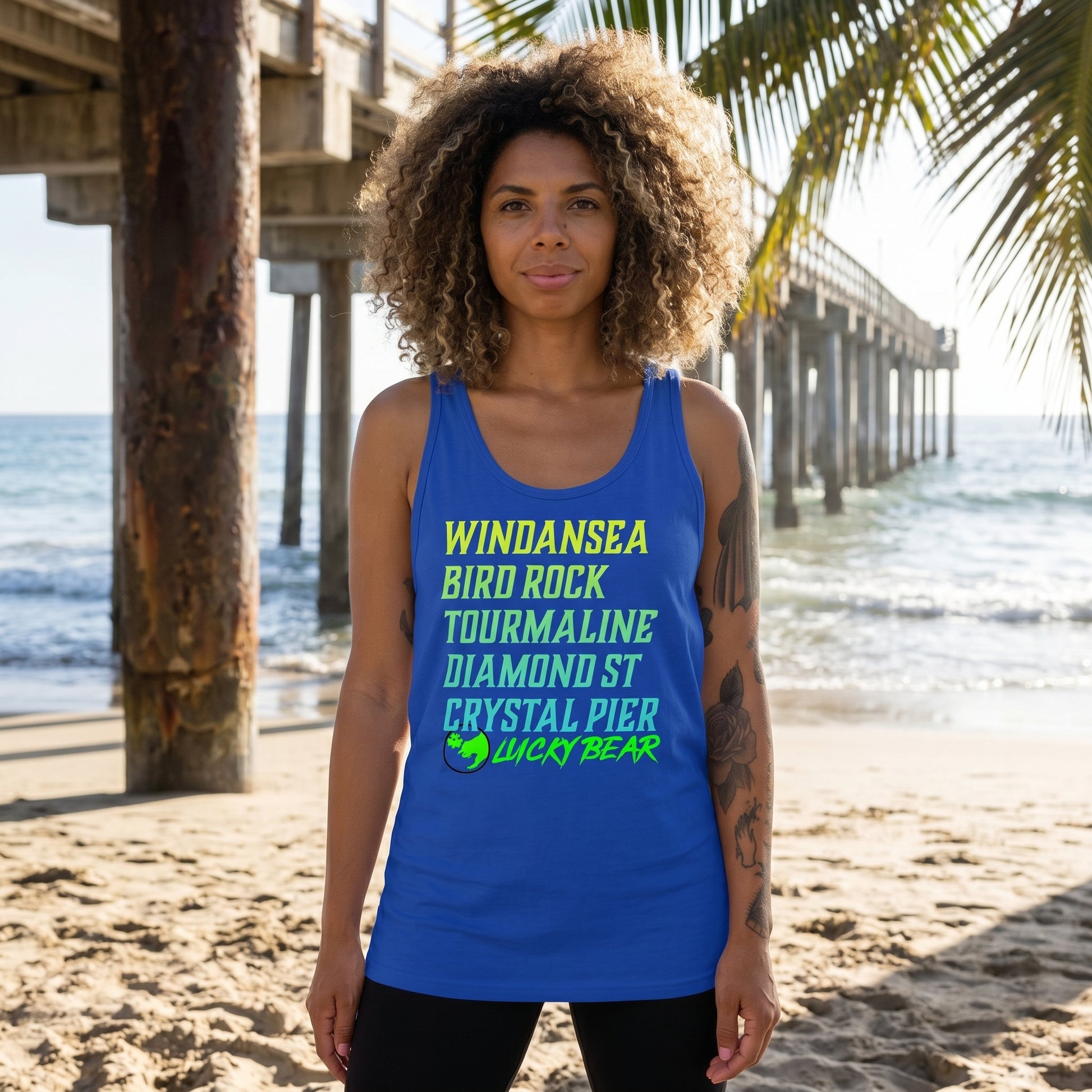 Model wearing Lucky Breaks Tank Top at the beach next to a pier, showing relaxed fit and fabric texture with natural outdoor lighting.
