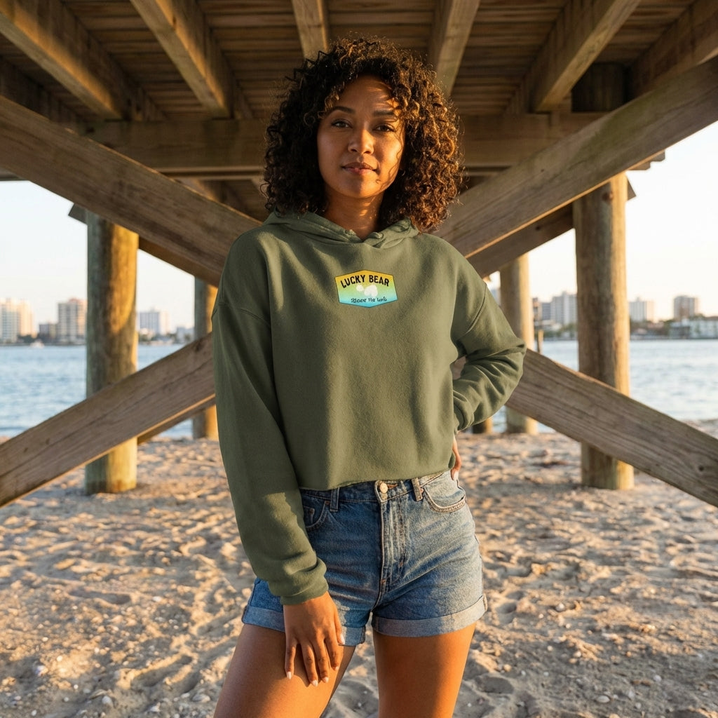 Model in orange crop hoodie with dropped shoulder cut and raw hem, wearing denim shorts during golden hour near a pier.