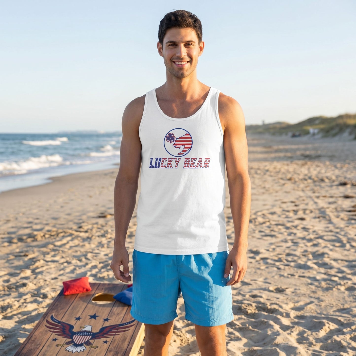 Full-body shot of a model wearing the All American Luck men's tank top playing corn hole on a beach at golden hour, showcasing fit and fabric.