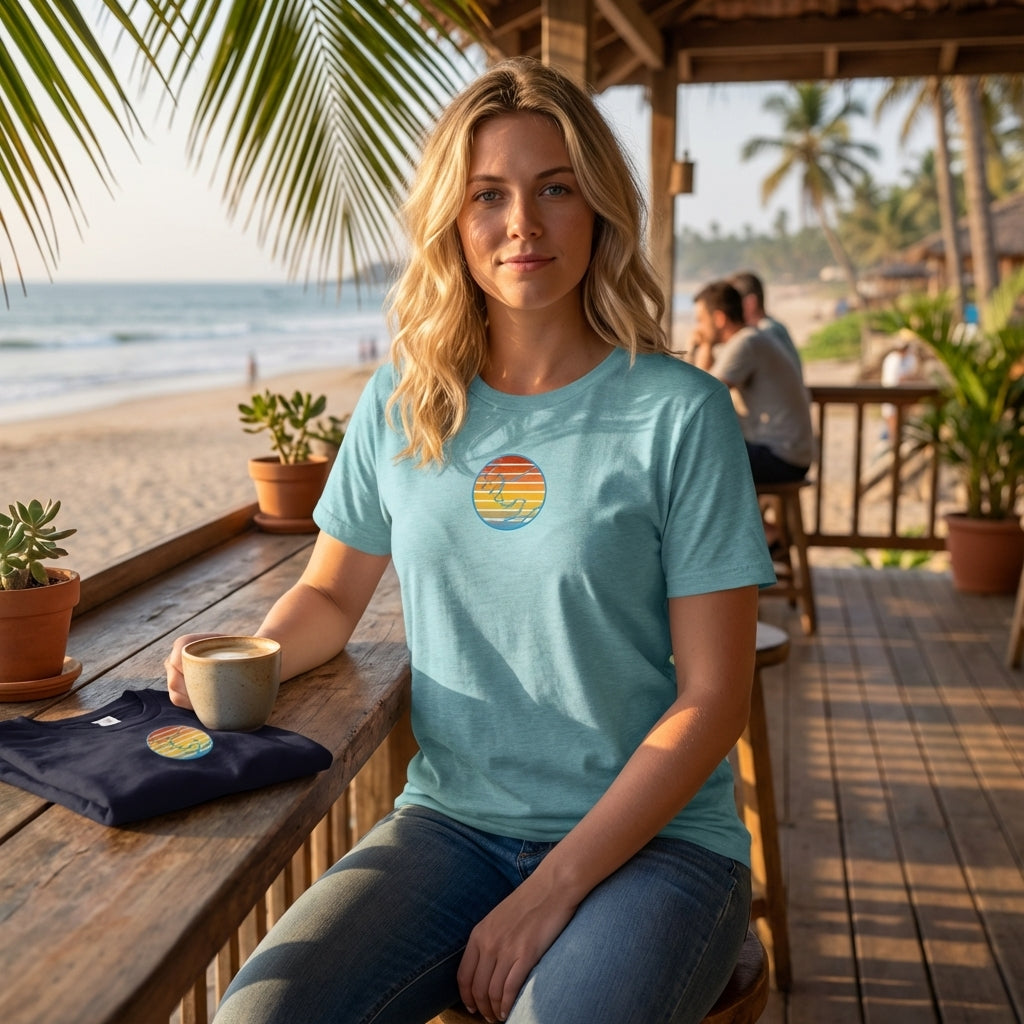 Full-body shot of woman wearing relaxed fit sunset T-Shirt at outdoor cafe by the ocean, showing fit, drape, and color in natural light.