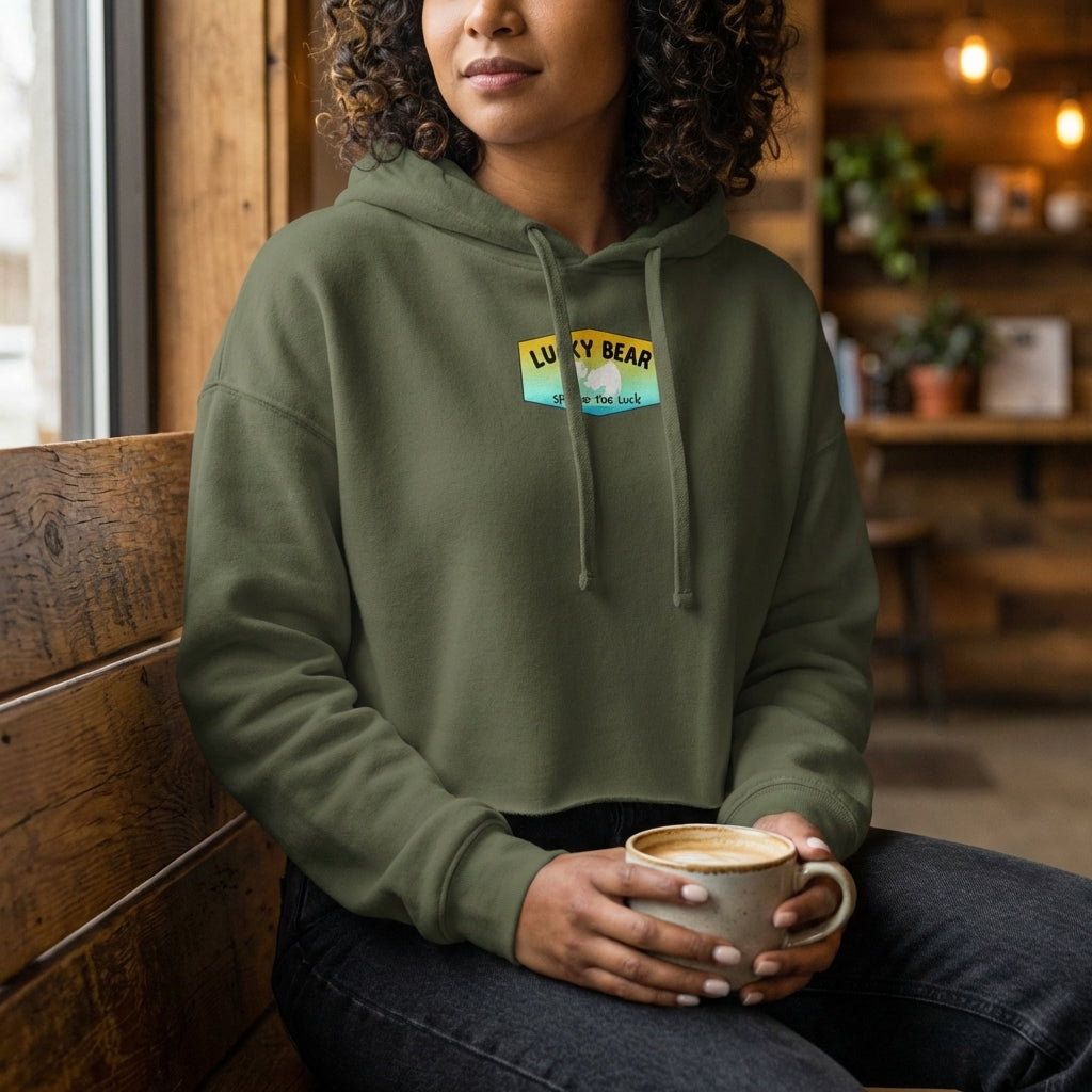 Indoor scene with a model in Orange Dreaming Crop Hoodie sitting on a rustic wooden bench, emphasizing fabric and drawstring details.