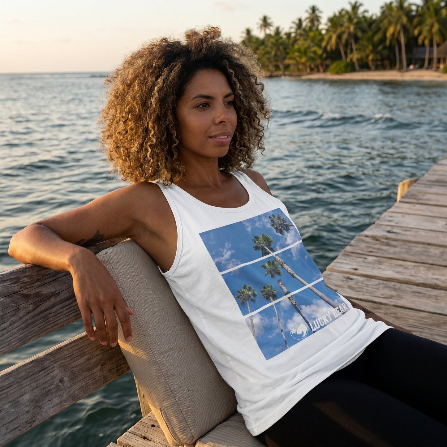 Person relaxing on a dock wearing Palm View Tank Top, capturing fabric details and ocean backdrop.