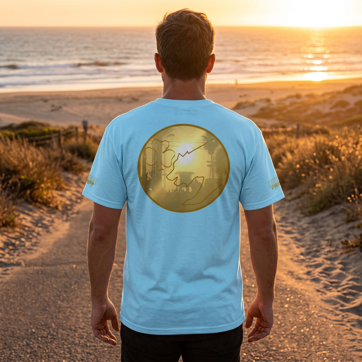 Male model walking on a sandy beach road at sunset wearing the San Diego Sunset men's cotton tee, showcasing fabric details and stitching.