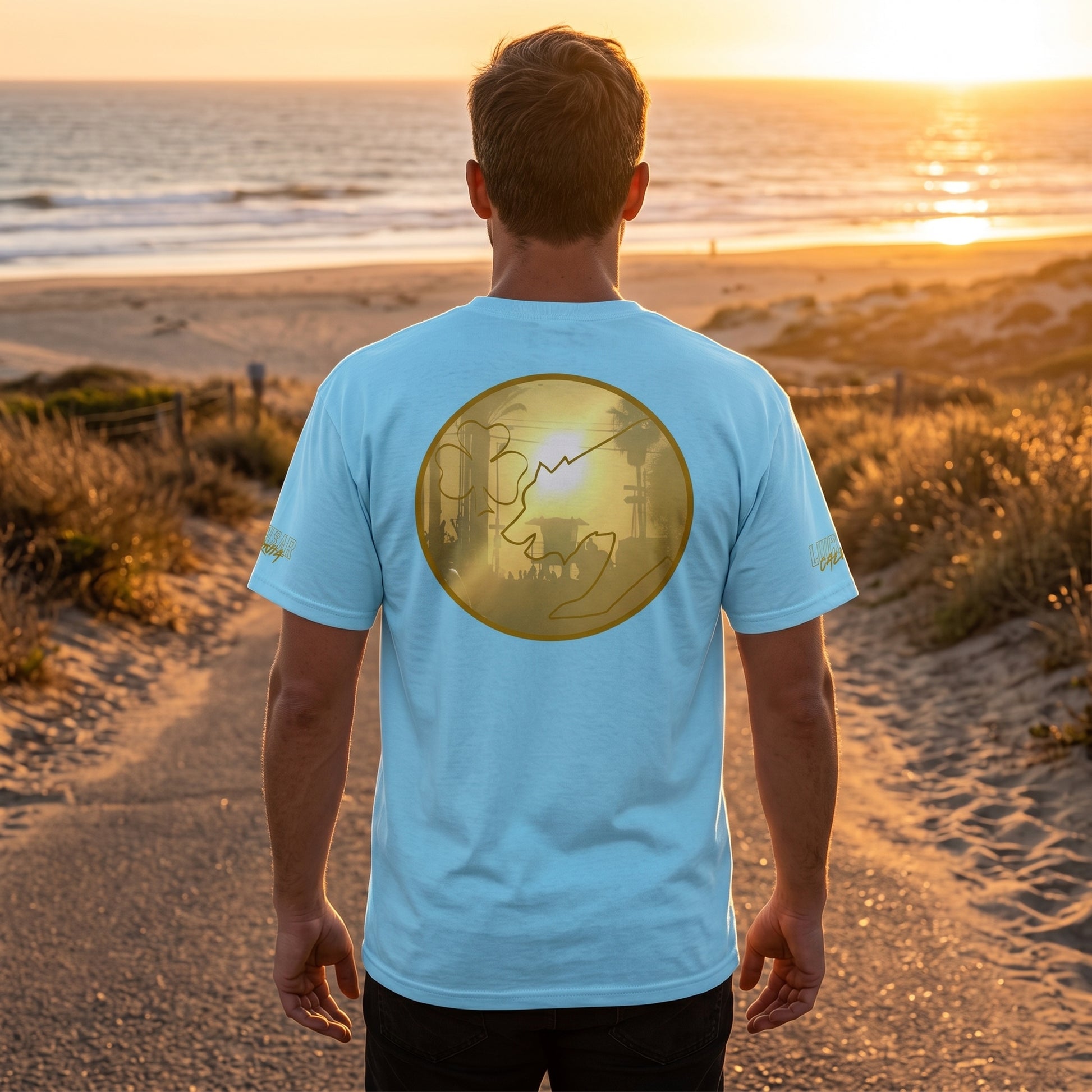 Male model walking on a sandy beach road at sunset wearing the San Diego Sunset men's cotton tee, showcasing fabric details and stitching.