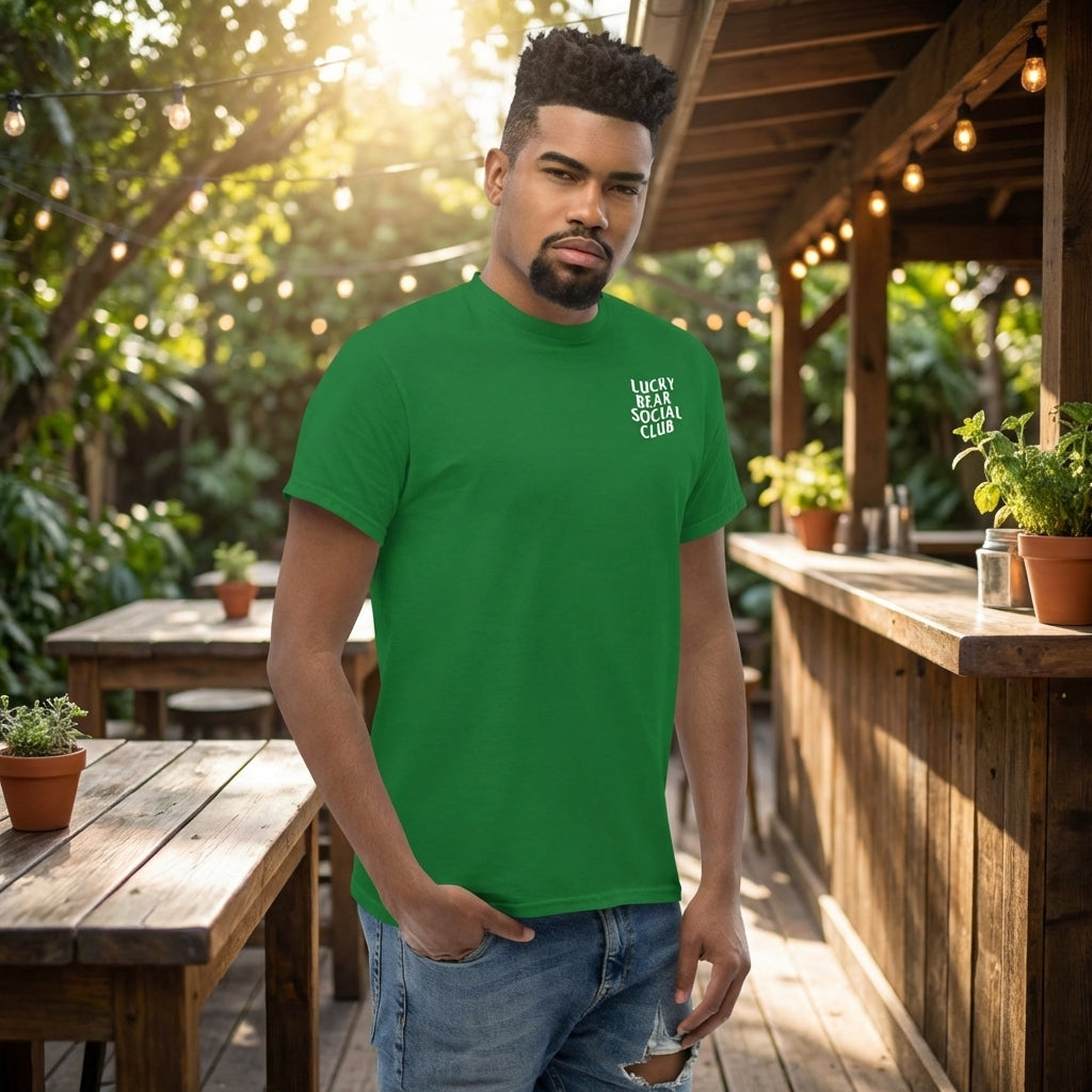 Full-body view of a model wearing Lucky Bear Social Club T-shirt outdoors, showing fit and logo with a blurred greenery background.