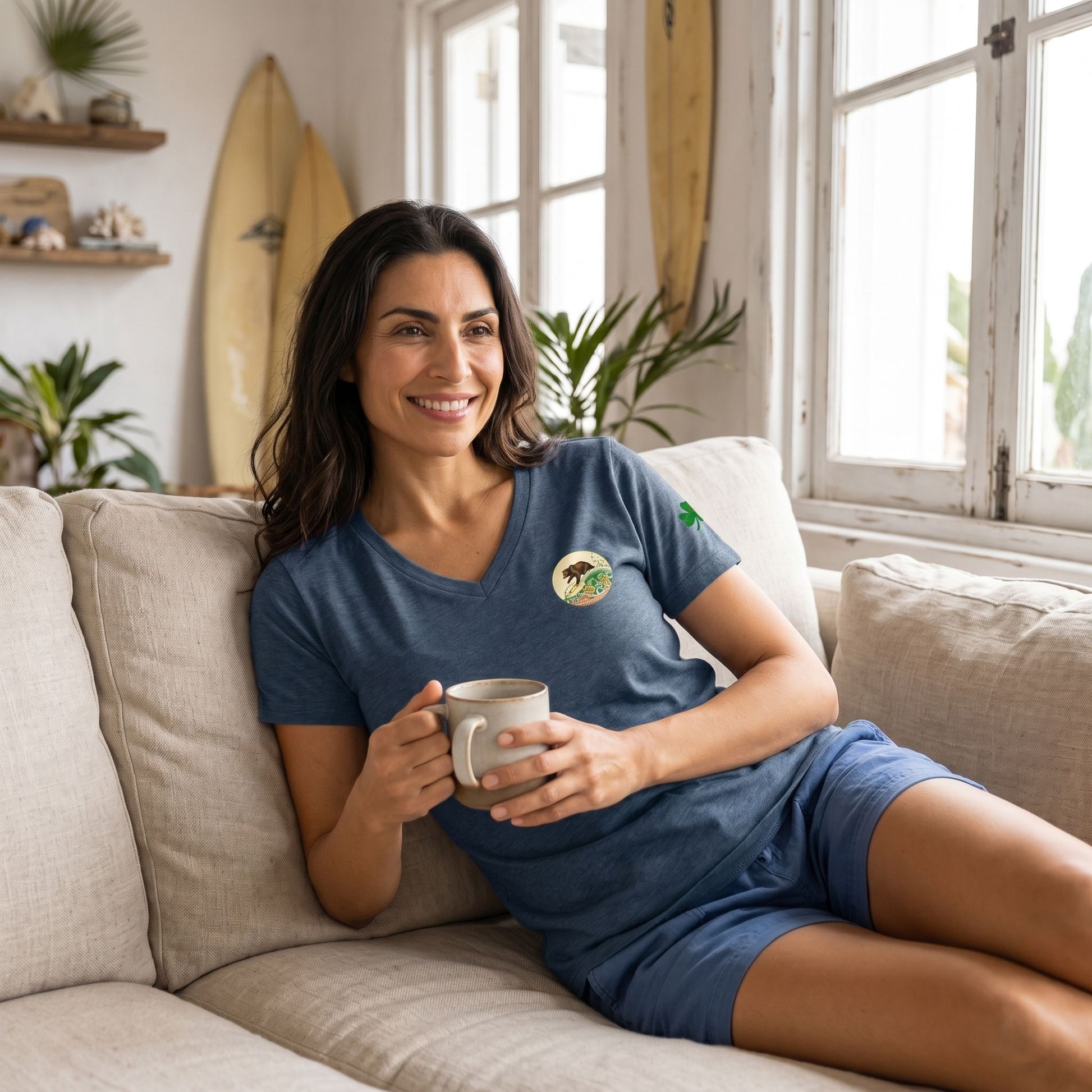 Close-up of women's Surf Club v-neck t-shirt on relaxed model in beach house with coastal decor and surfboards