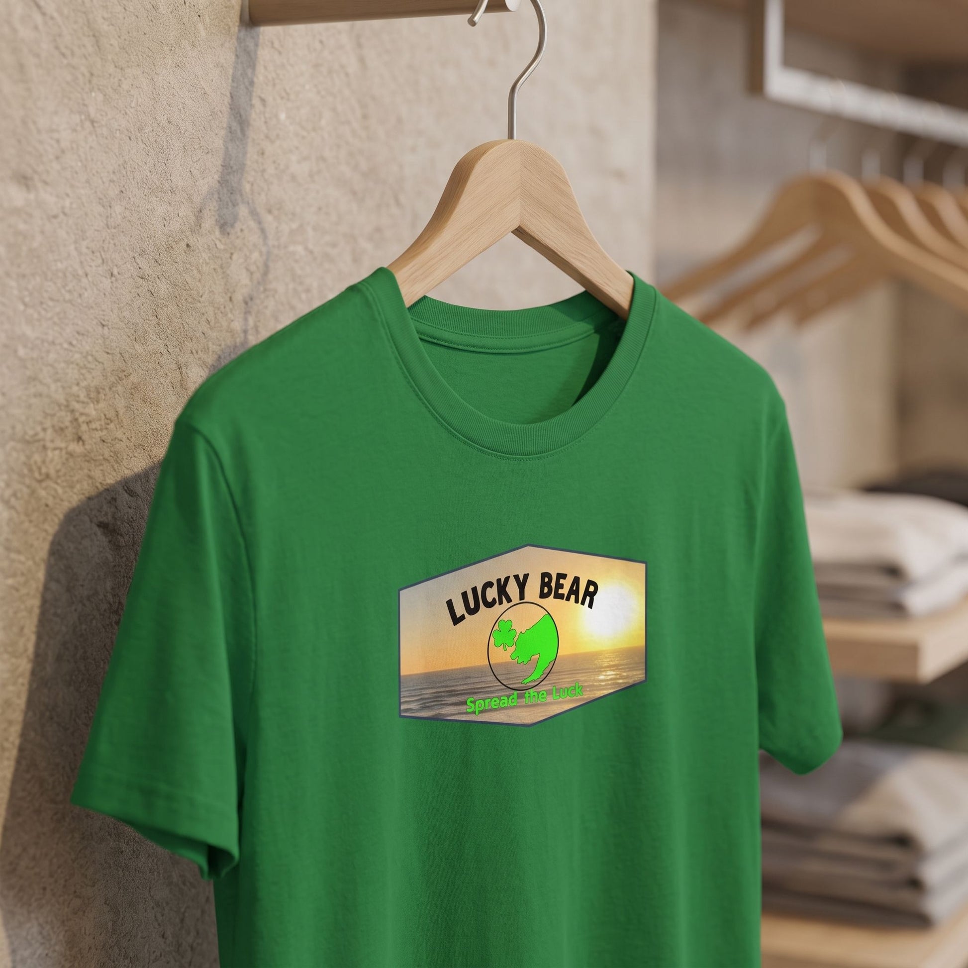 Close-up of Spread the Luck Sunset tee on hanger in retail setting with soft lighting and neutral background.