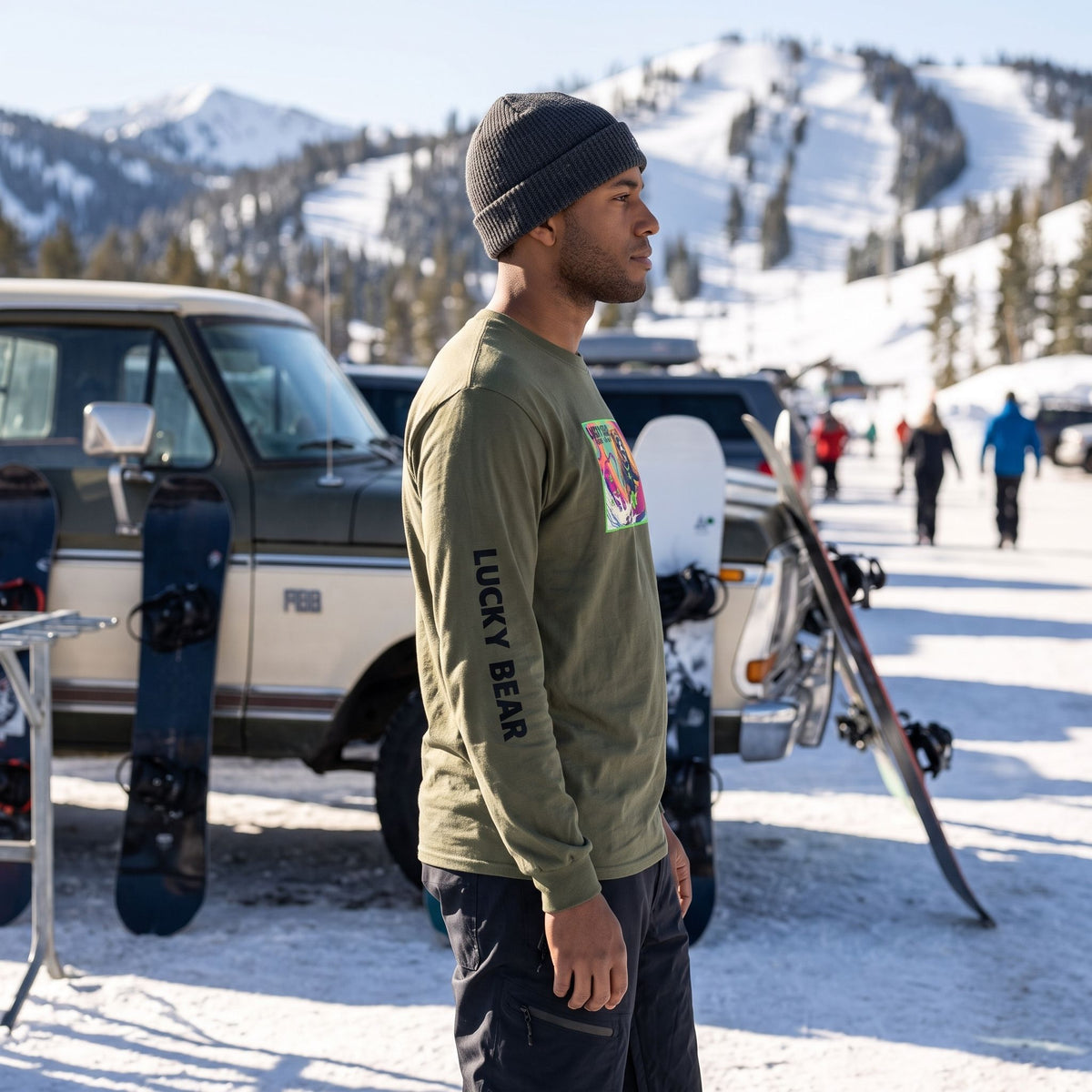 Model wearing a Sierra long-sleeve shirt with snow gear at a ski resort parking lot.