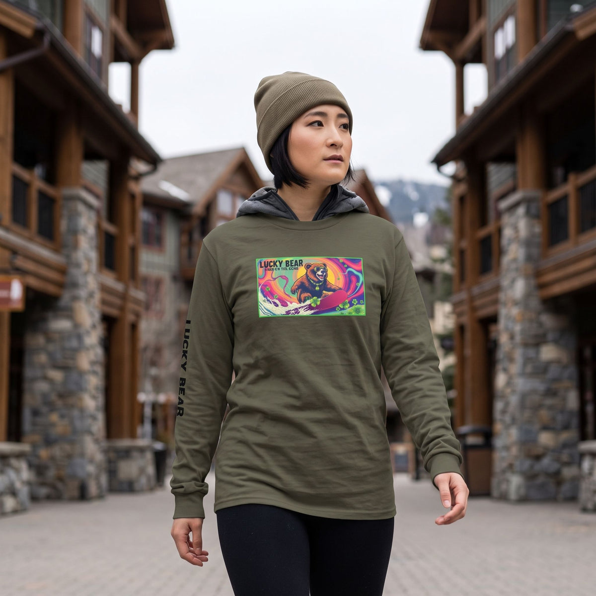 Woman wearing a Sierra Bear Trip long-sleeve shirt with a surfing bear graphic while walking through a mountain ski village.