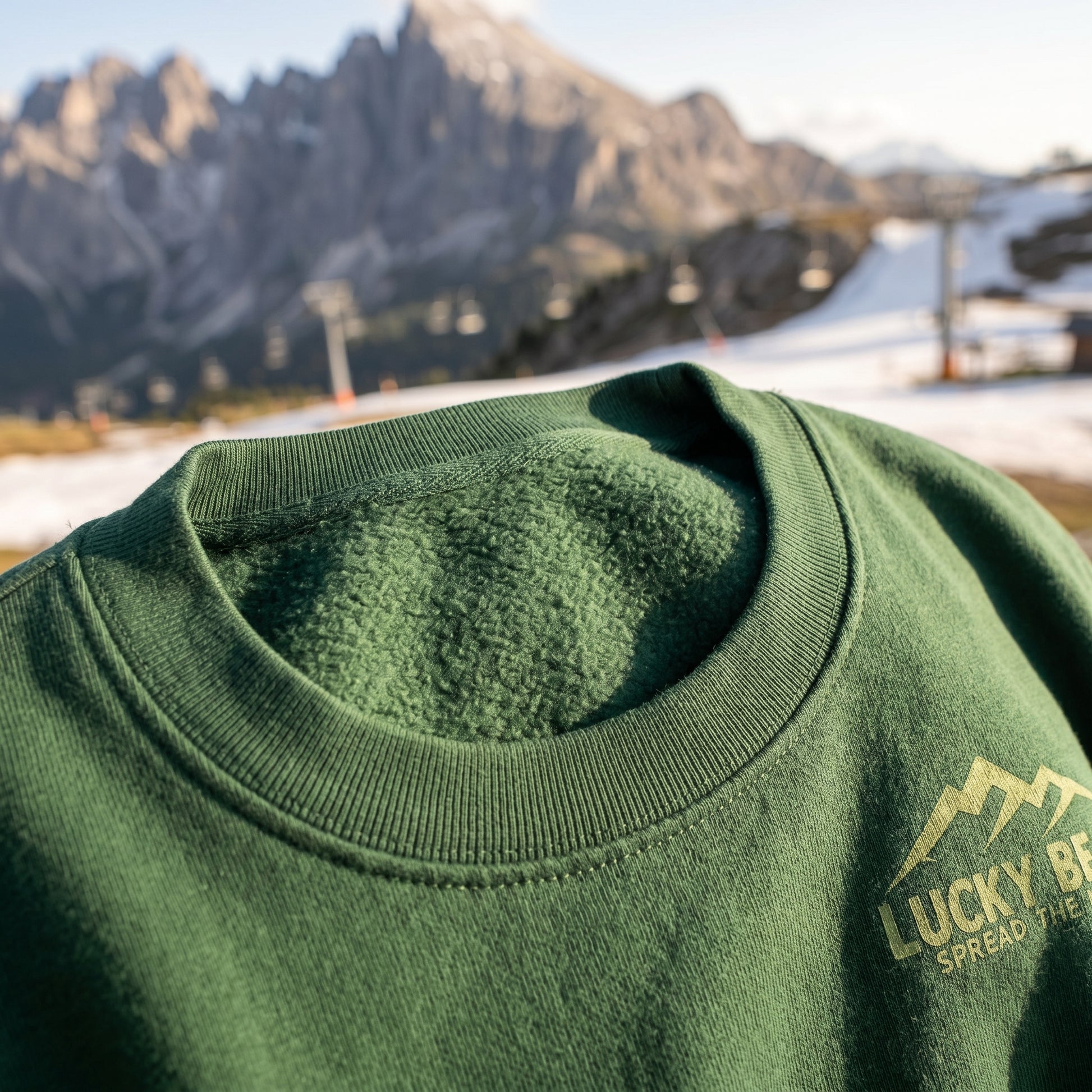 Close-up of Sierra Summit Premium Sweatshirt highlighting fleece interior, ribbed crew neck, and mountain-inspired design with outdoor ski scenery.