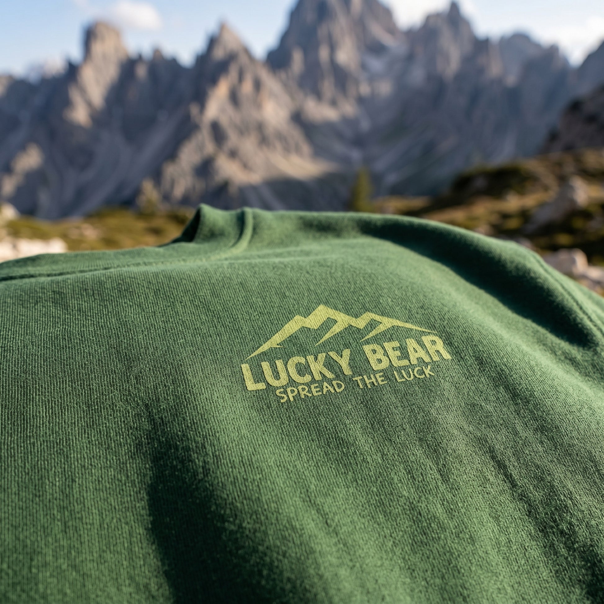 Close-up of Sierra Summit Premium Sweatshirt's chest logo showing fine knit texture and mountain scenery background.