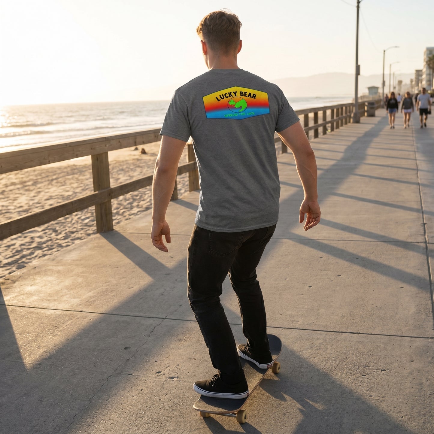 Back view of a skater wearing the Sunset Ombre Classic Tee, highlighting the draped fabric and sunset gradient on an urban boardwalk at golden hour.
