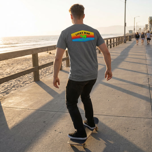 Back view of a skater wearing the Sunset Ombre Classic Tee, highlighting the draped fabric and sunset gradient on an urban boardwalk at golden hour.
