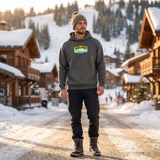 Full-body of a model wearing the Summer Sunset Hoodie in a ski resort street scene during golden hour, showcasing relaxed fit and street style.