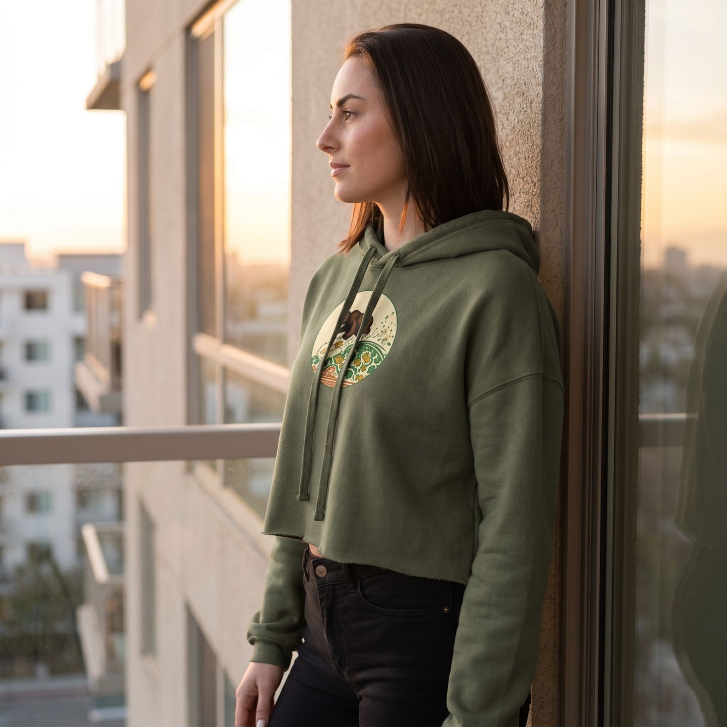 Side profile of a model wearing the Surf Club Crop Hoodie on a balcony at sunrise, highlighting fabric and shape.
