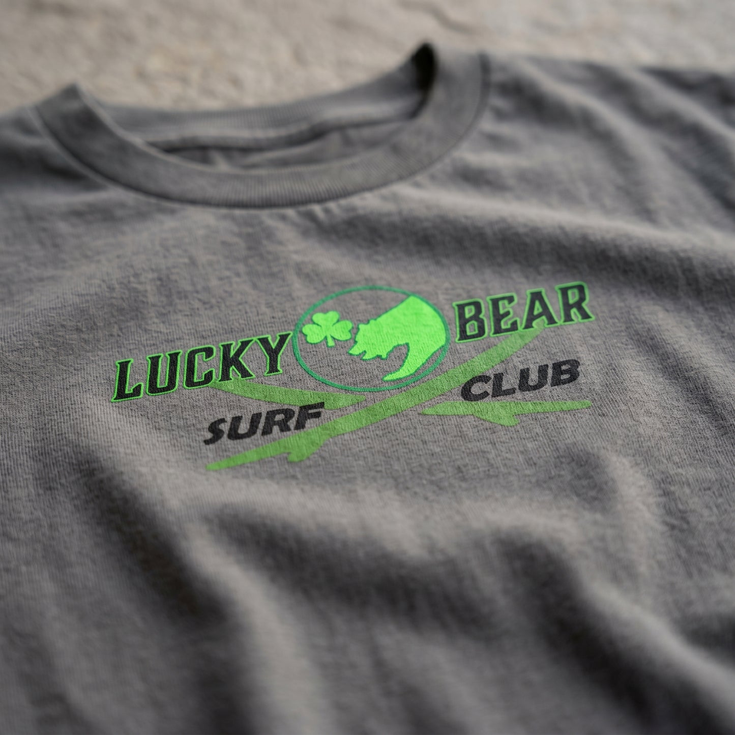 Close-up of Surf Club Logo Youth Tee fabric highlighting crisp micro-texture, logo clarity, and soft slightly wrinkled material in natural daylight.