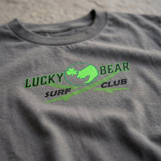 Close-up of Surf Club Logo Youth Tee fabric highlighting crisp micro-texture, logo clarity, and soft slightly wrinkled material in natural daylight.
