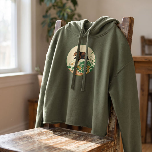 Close-up of Surf Club Old School Crop Hoodie showing thick weave and detailed stitching on a rustic wooden chair with natural daylight highlighting the fabric texture.