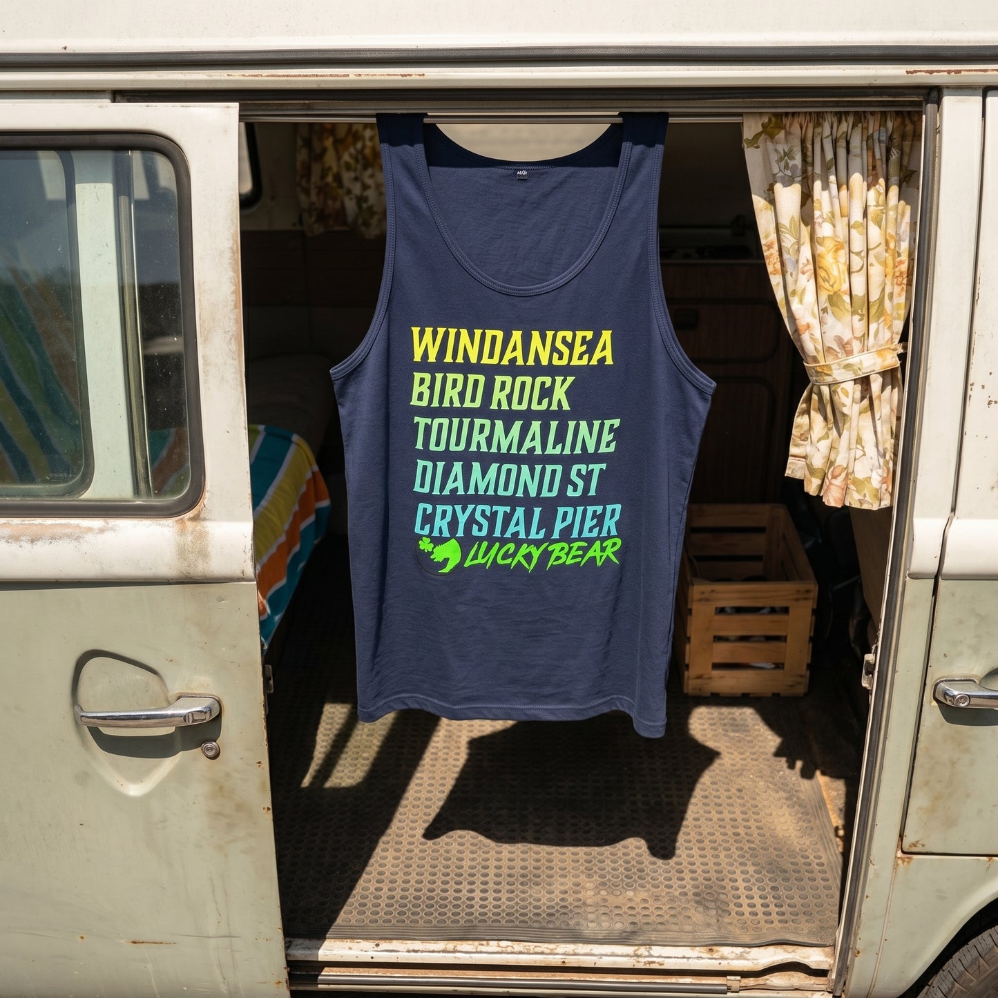 Overhead shot of navy and royal Lucky Breaks Tank Top hanging from vintage VW van's sliding door, highlighting fabric texture and silhouette.