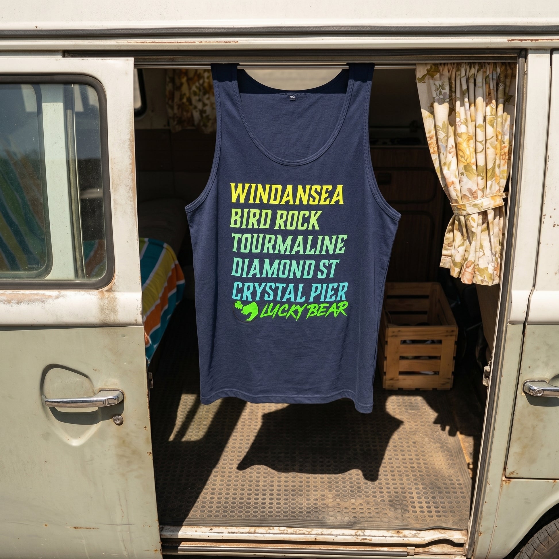 Overhead shot of navy and royal Lucky Breaks Tank Top hanging from vintage VW van's sliding door, highlighting fabric texture and silhouette.