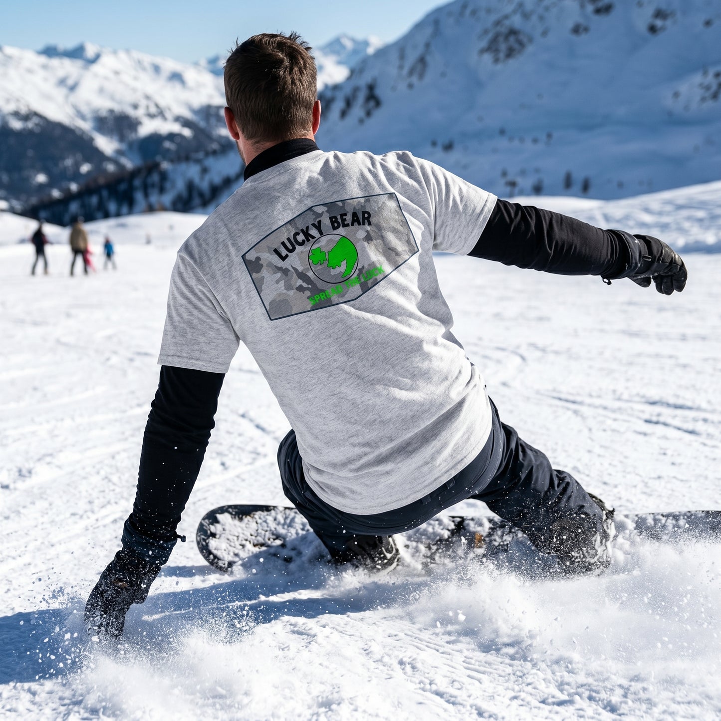 Outdoor winter action shot of a rugged model in snow, showcasing the back of a black long sleeve shirt with 'Spread the Luck' graphic, emphasizing durability and outdoor adventure.