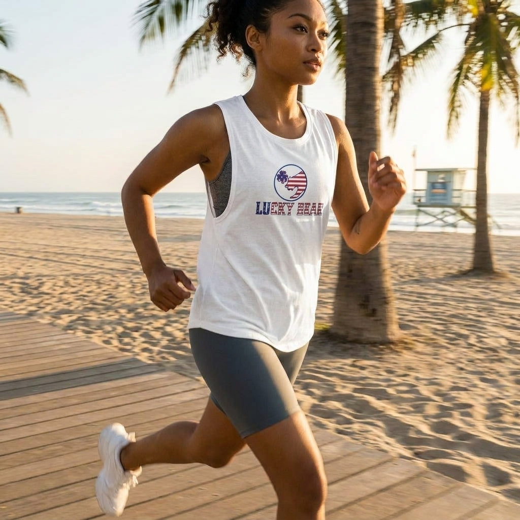 Action shot of a woman jogging by the beach during golden hour, wearing a flowy muscle tank with relaxed fit and low armholes, highlighted in vibrant outdoor light.