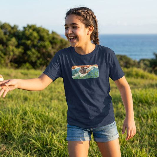 Young girl in Surf Club Retro Bear Youth Tee playing outdoors during golden hour with lush greenery and ocean hints, showcasing the comfortable cotton fabric.