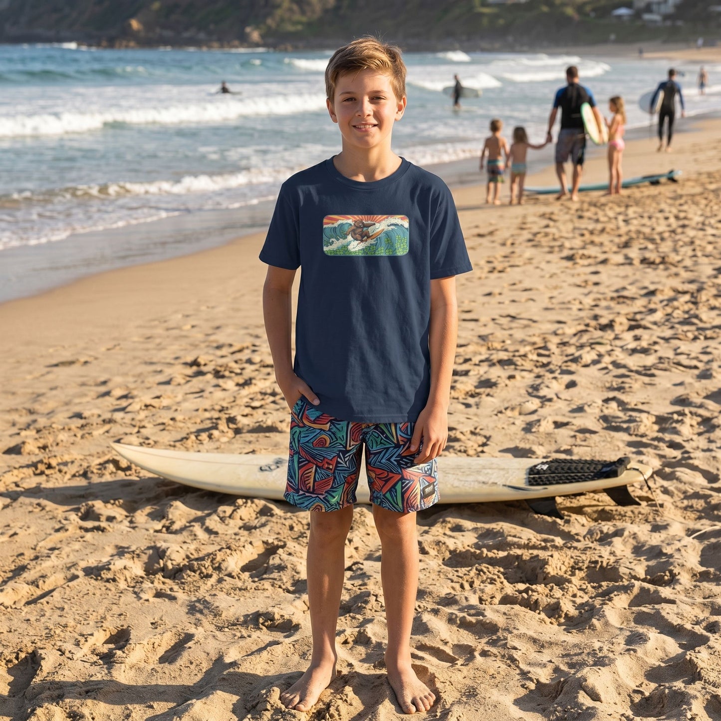 Caucasian kid wearing Surf Club Retro Bear Youth Tee standing on a sandy beach with a surfboard, casual pose, natural sunlight, ocean background.