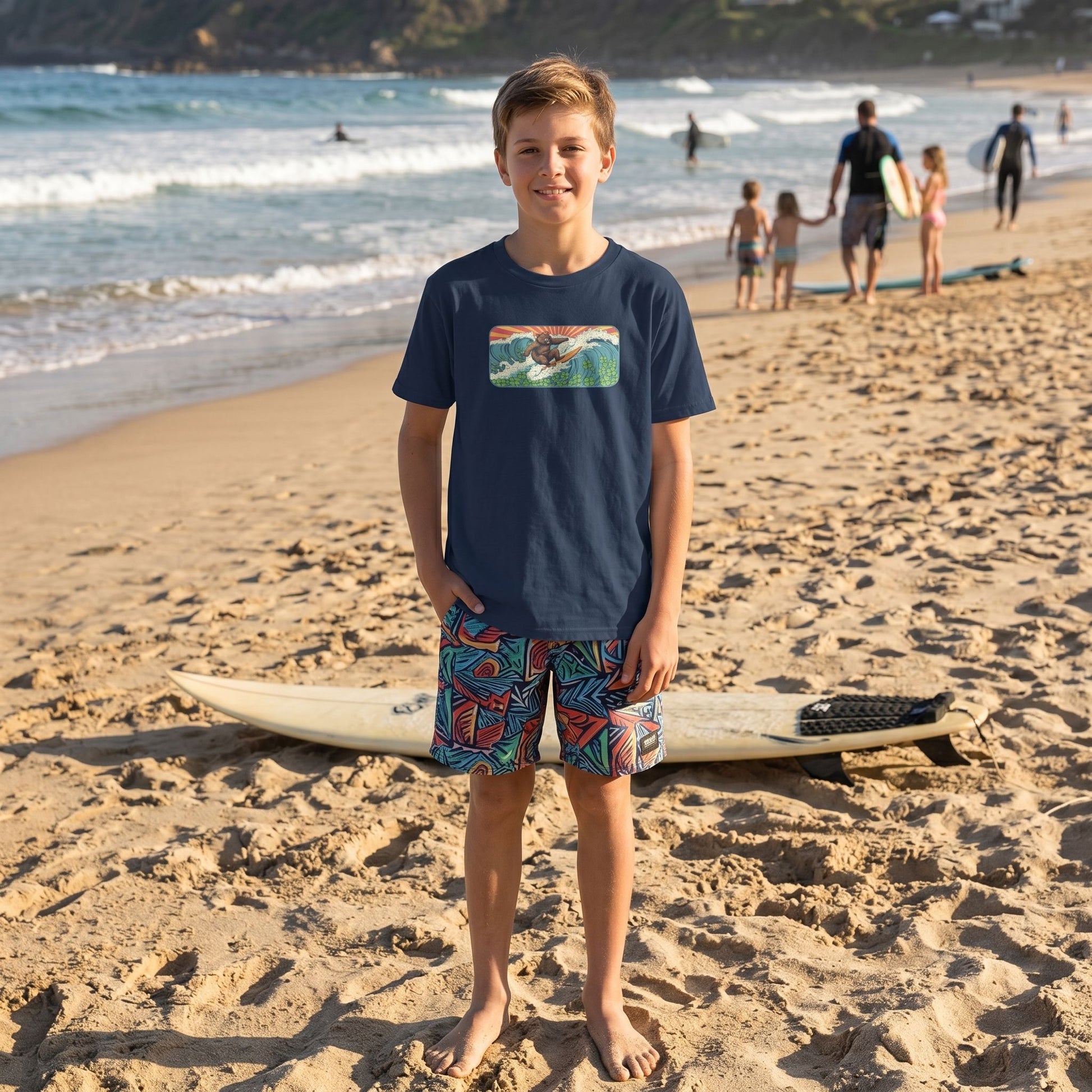 Caucasian kid wearing Surf Club Retro Bear Youth Tee standing on a sandy beach with a surfboard, casual pose, natural sunlight, ocean background.